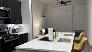 Una cocina moderna con armarios oscuros, una isla central y un ventilador de techo.