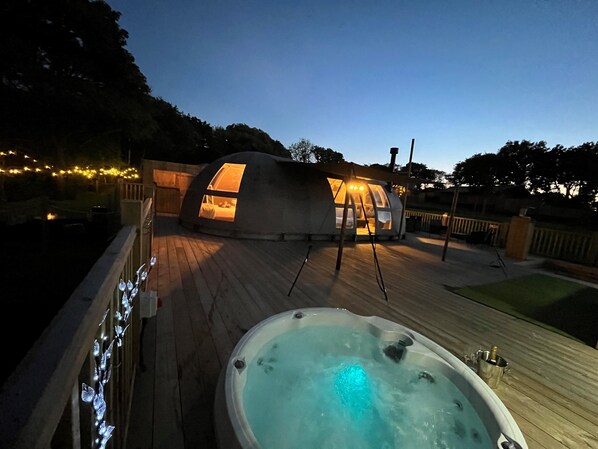A dome-shaped structure with a hot tub in the foreground and a wooden deck. - Moonlight Tent (Tenby)