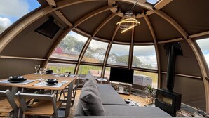 A cozy interior with a dining table, chairs, a sofa, and a fireplace. - Moonlight Tent (Tenby)