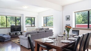Una sala de estar moderna con comedor, ventanas amplias y televisor de pantalla plana.
