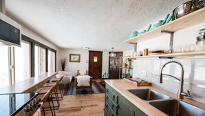 Une cuisine moderne avec un long comptoir, une cuisinière et un évier. On y trouve des tabourets de bar et un tapis sur le sol.