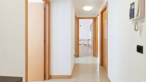 Un pasillo con puertas de madera, un teléfono en la pared y suelo de baldosas.
