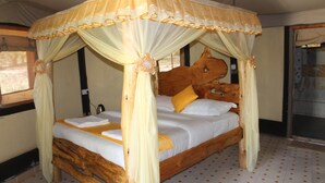 A wooden four-poster bed with a canopy, white bedding, and a single yellow pillow. - Explore Mara Camp (Maasai Mara)