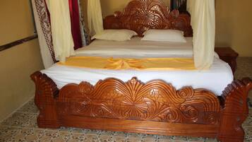 A wooden four-poster bed with a white bedspread and yellow decorative ribbon.