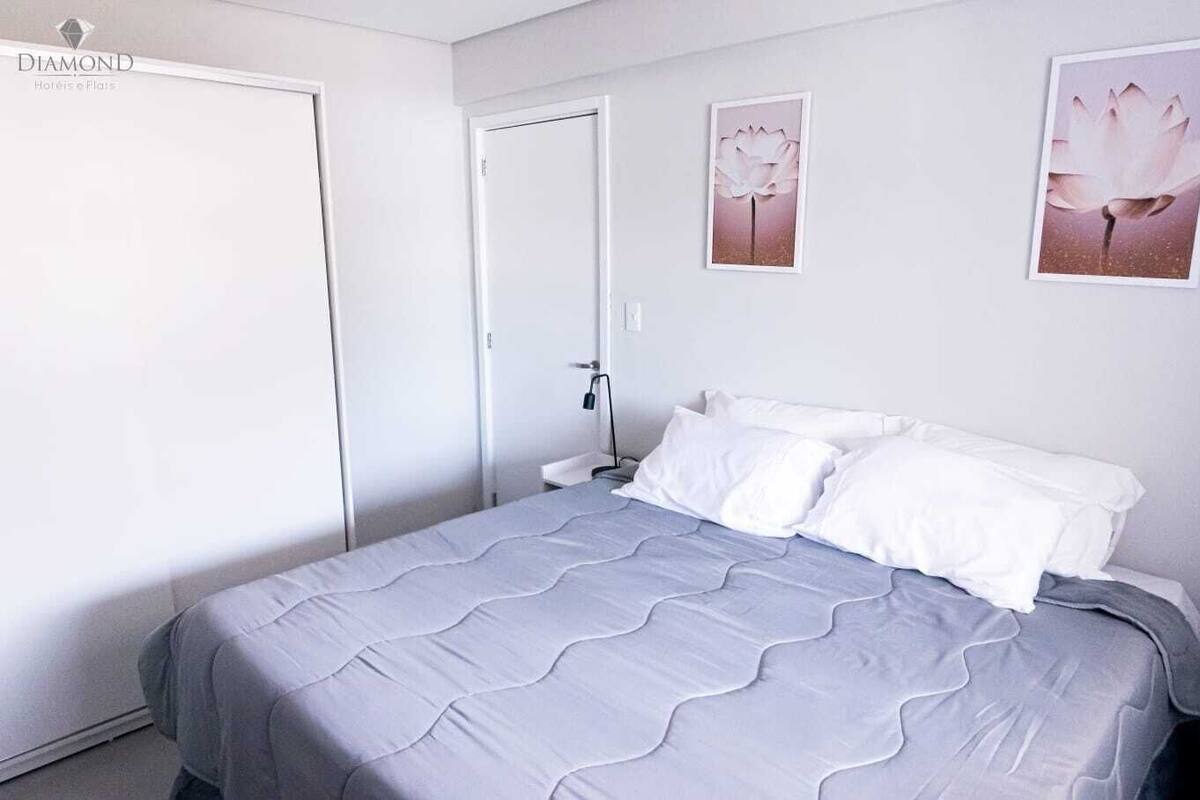 Une chambre à coucher avec un lit, des oreillers, une table de chevet, une porte et des œuvres d’art mural.
