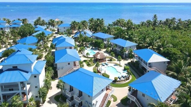Un resort con varias edificaciones, una piscina central y vista al océano.