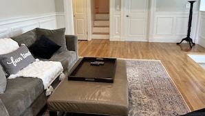 Una sala de estar con un sofá gris, una mesa de centro y una alfombra estampada.
