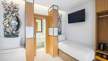 A hotel room with two single beds, wooden paneling, a large abstract artwork on the wall, a flat-screen TV, and a coffee maker on the nightstand.