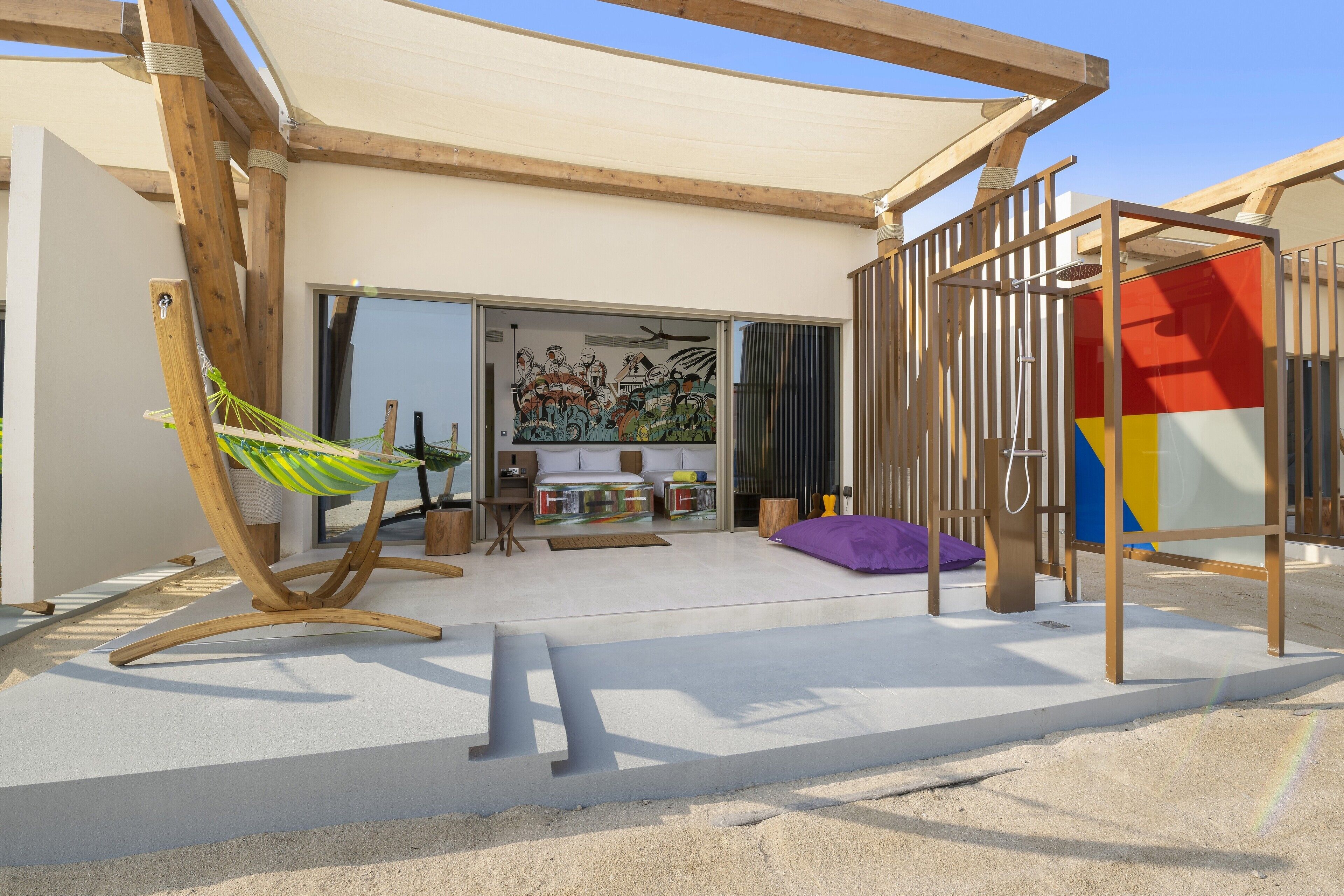 Un espacio exterior moderno con una hamaca, un área de juegos y un muro de colores.