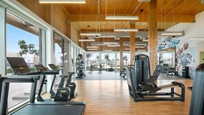 Ein Fitnessraum mit Laufbändern, Krafttrainingsgeräten und einer großen Spiegelwand.