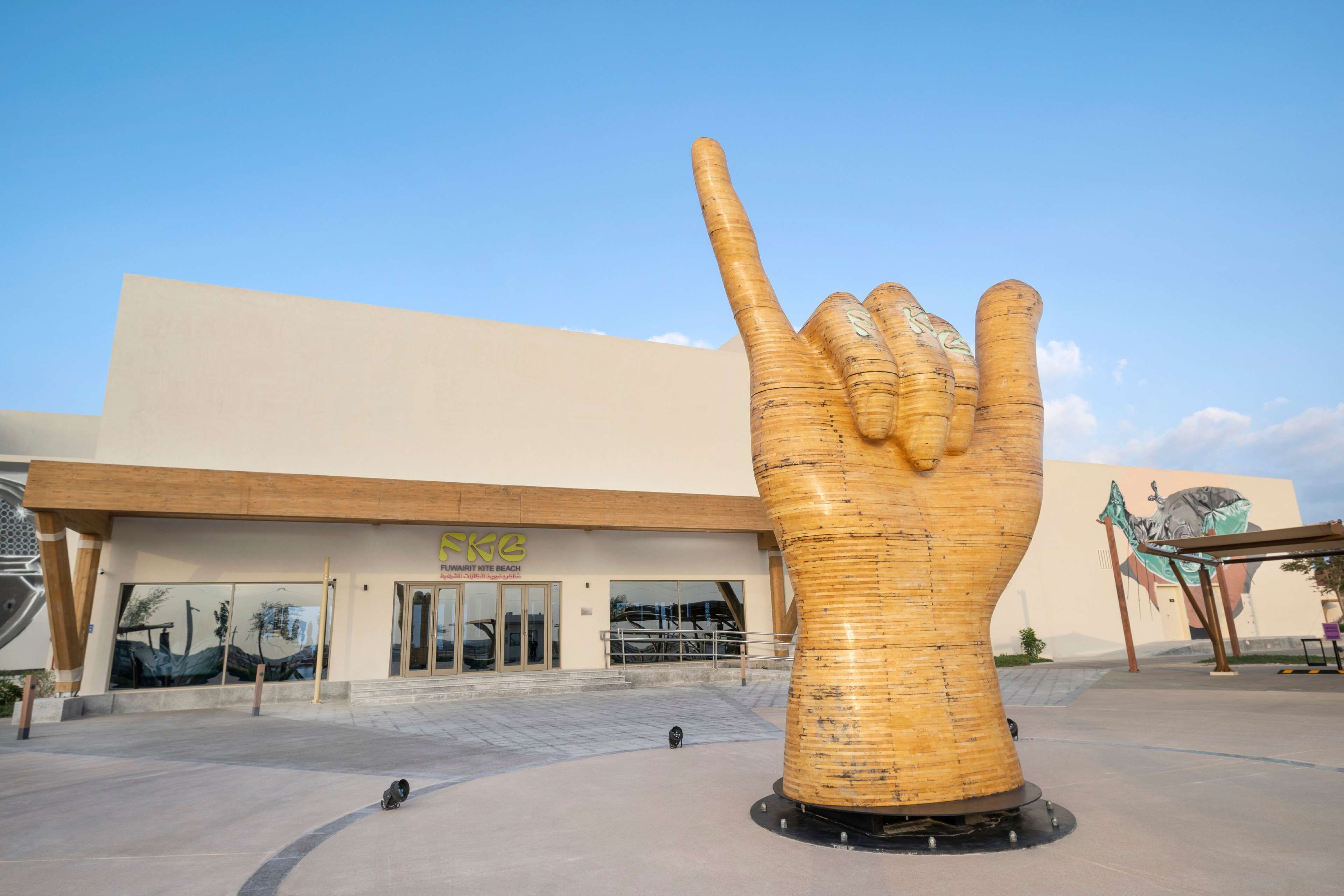 A large golden hand sculpture in front of a building with a sign reading "RIMAK".