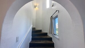 Una escalera con una pared blanca y una ventana al final.