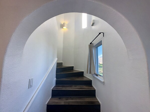 Una escalera con una pared blanca y una ventana al final.