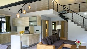 Un espace de vie moderne comprenant une cuisine, un canapé, une table basse et un escalier.