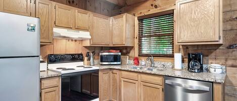 Une cuisine dotée de meubles en bois, d’un lave-vaisselle en acier inoxydable, d’un four à micro-ondes, d’une cuisinière et d’un réfrigérateur.