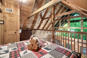 A wooden interior with a bed, a wooden dresser, and a window overlooking greenery.