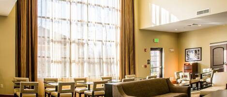 A hotel lobby with a large window, seating area, and a television.