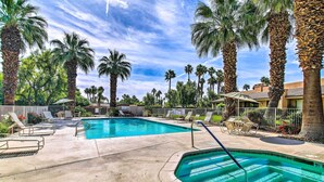 A swimming pool surrounded by palm trees and lounge chairs. - Patio + Resort Amenities: Palm Desert Escape (Palm Desert)