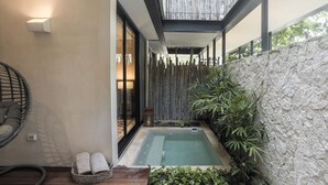 Un área de spa con un jacuzzi, una silla de mimbre y una mesita con toallas.
