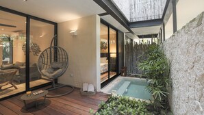 Un área exterior moderna con jacuzzi, una silla colgante y una terraza de madera.