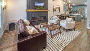 A modern living room with a fireplace, a dining area, and a kitchen. - Stunning, Newly Renovated Villa! Close to Strip #2 (Pigeon Forge)