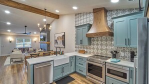 A modern kitchen with light blue cabinets, a central island, stainless steel appliances, and a patterned backsplash. - Stunning, Newly Renovated Villa! Close to Strip #2 (Pigeon Forge)