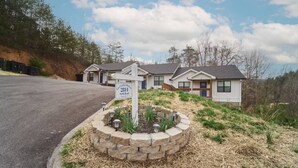 A row of single-family homes with a stone retaining wall and a sign indicating the address. - Stunning, Newly Renovated Villa! Close to Strip #2 (Pigeon Forge)