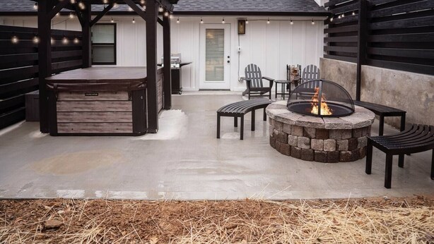 An outdoor patio with a stone fire pit, wooden chairs, and a pergola with string lights. - Stunning, Newly Renovated Villa! Close to Strip #2 (Pigeon Forge)