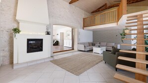 Amplia sala de estar con chimenea, un conjunto de sofás, una escalera y vistas a la cocina.