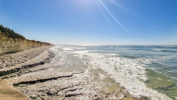 Una playa con costa rocosa y cielo despejado.