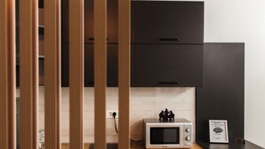 Een moderne keuken met zwarte kastjes, een houten aanrechtblad, een magnetron en een hangende lamp.