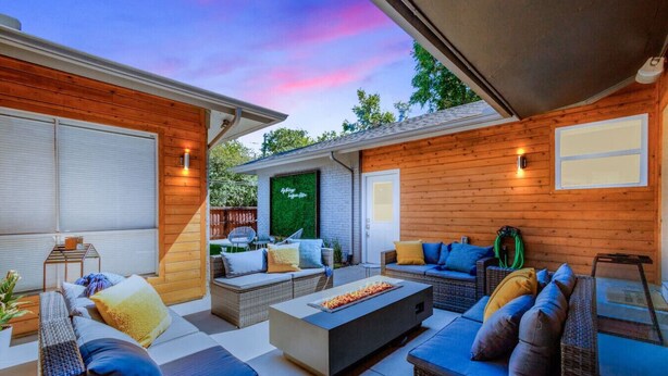 Un espacio al aire libre techado con mobiliario de mimbre, una chimenea y un muro cubierto de vegetación.