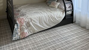 A bunk bed with a ladder, a decorative wall piece, and a window with curtains.