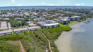 An aerial view of a coastal residential area with buildings, a beach, and a marina.