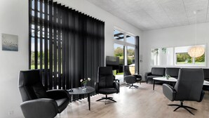 Un espacio de oficina moderno con sillas de cuero negro, una mesa redonda y ventanas amplias con vistas a zonas verdes.