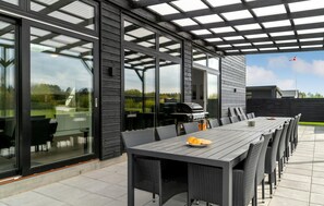 Relax on the patio with a long table and comfortable seating, perfect for outdoor dining and grilling.