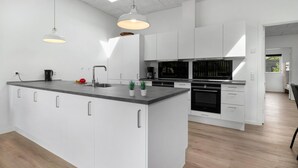 Una cocina moderna con armarios blancos, una isla central y un horno empotrado.