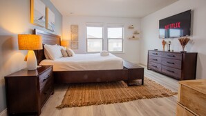 A bedroom with a bed, nightstands, a dresser, a TV, and a window. - Luxury 5bd townhome | Gated Resort Community (Kissimmee)