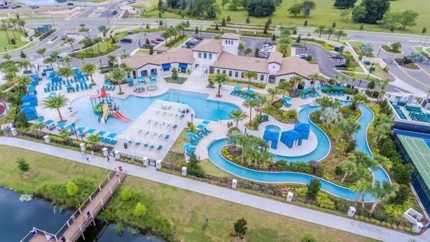 An aerial view of a resort with a large swimming pool, a water slide, and a winding water feature. - Luxury 5bd townhome | Gated Resort Community (Kissimmee)