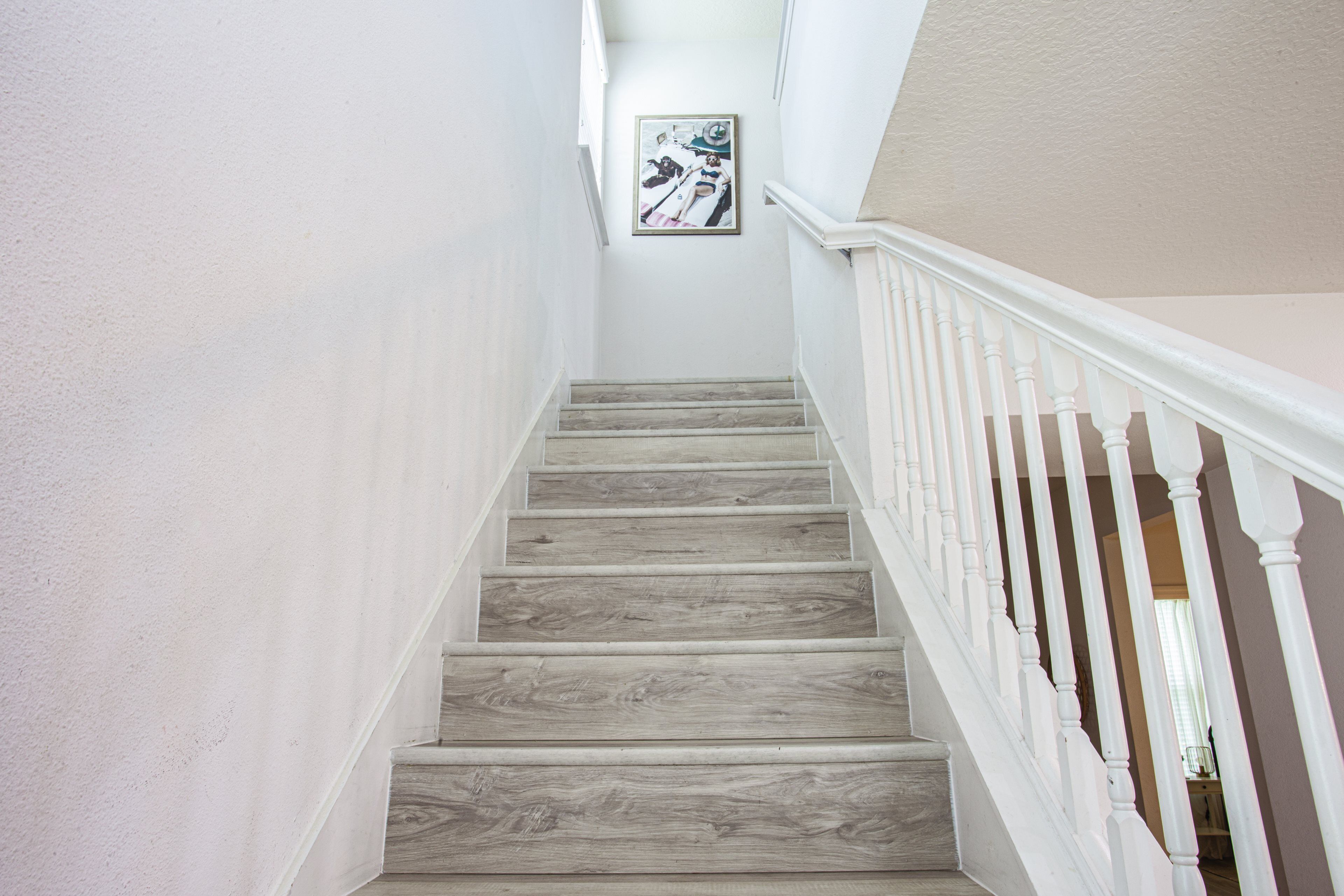 Una escalera con escalones de madera y barandillas blancas.