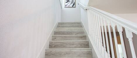 Una escalera con escalones de madera y barandillas blancas.