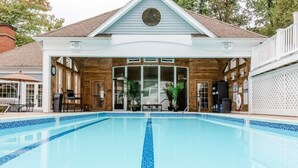 A swimming pool with a wooden deck area, a covered seating area, and a house with a gabled roof in the background. - ROMANTIC SPA RETREAT MINUTES TO MOHEGAN SUN CASINO (Norwich)