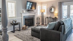 Una sala de estar con chimenea, televisor, escritorio y sofá.