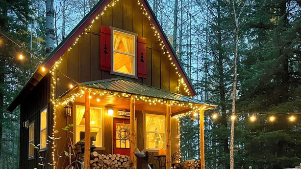 Eine Hütte mit Veranda, Feuerstelle und einem roten Stuhl.