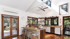 A spacious kitchen with a large island, wooden flooring, and a ceiling fan.