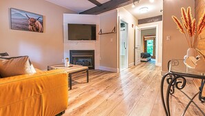 A modern living room with a sofa, a fireplace, and a television. - Chimney Hill - 02) First-Floor Suite 2 (Lambertville)