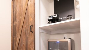 A room with a wooden sliding door, a coffee machine, a refrigerator, and a 'Welcome' sign on the wall. - Chimney Hill - 02) First-Floor Suite 2 (Lambertville)