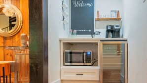 Een kleine keuken met een magnetron, koffiezetapparaat en een 'Welcome' bord.