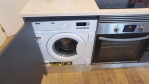 Máquina de lavar e secar compacta com painel de controle, visor digital e forno de aço inoxidável.
