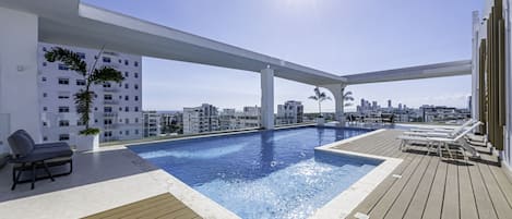 Una piscina al aire libre, sillones reclinables de piscina